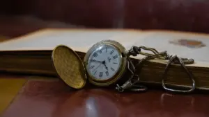 Antiikne taskukell avatud raamatu peal sümboliseerimas ajaloo ja aja sügavat seost.