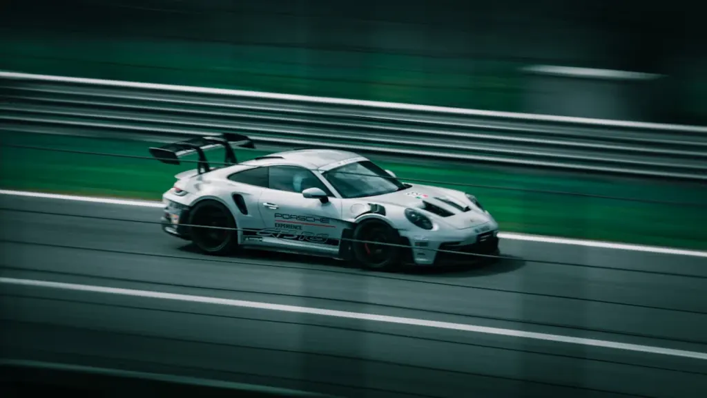 Valge Porsche Carrera võidusõiduauto kiiresti kihutamas Pärnu Porsche Ringi rajal.